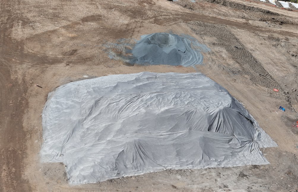 Aerial view of a covered stockpile on an earthworks site, outlined at its toe with its measured volume